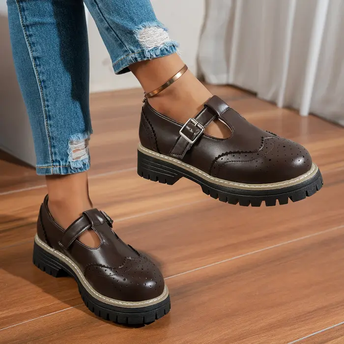 Chaussures plates noires à bride en T pour femmes, bout rond avec détail brogue et boucle métallique